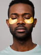 © ohlamour studio/Stocksy - Relaxed man using gold under eye mask