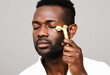 © ohlamour studio/Stocksy - Man massaging his face with electric roller