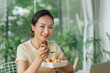 © Marc Tran/Stocksy - Woman eats food ordered at delivery service while sitting in her