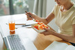 © Marc Tran/Stocksy - Woman eating food from take away lunch box at workplace
