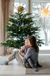 © Sergey Narevskih/Stocksy - Woman and child hugging under Christmas tree at home