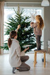 © Sergey Narevskih/Stocksy - Woman with child decorating Christmas tree