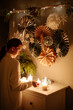 © Sergey Narevskih/Stocksy - Woman lighting candles at Christmas time at home