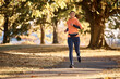 © Drazen - Young happy sportswoman running in park during autumn day.
