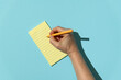 © Pixel Stories/Stocksy - Hand ready to write on post-it notebook.