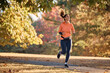 © Drazen - Full length of happy sportswoman running in park during autumn day.