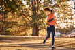 © Drazen - Happy athletic woman with earbuds running through park.