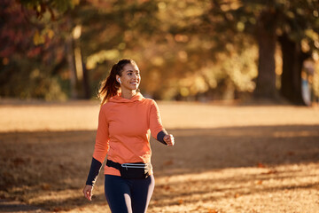 Poster - Happy sportswoman enjoys while walking in nature during autumn day.