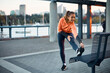 © Drazen - Happy female athlete stretching while working out outdoors.