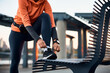 © Drazen - Unrecognizable sportswoman tying her shoelaces outdoors.