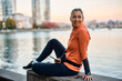 © Drazen - Happy athletic woman using smart phone while relaxing at riverbank.