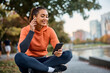 © Drazen - Happy female athlete using mobile app while listening music in park.