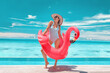 © Maridav - Travel Beach Vacation summer woman sunbathing relaxing with swimming pool pink flamingo float - funny luxury holiday travel concept woman in bathing suit and sunglasses on perfect sunny destination