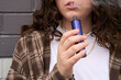 © Rowena Naylor/Stocksy - Young person vaping in street