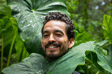 Portrait Of A Man Laughing In A Forest With  Huge Green Leaves