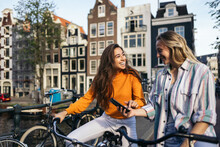 Friends looking at the mobile while riding a bike in Amsterdam