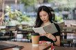 © Heng Yu/Stocksy - Young woman in a cafe reading an ebook