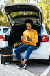 Male traveler using smartphone in car trunk