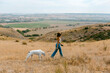 © Jimena Roquero/Stocksy - Young woman taking a walk with dog in the hills in a sunny day