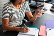 © Lightsy/Stocksy - Anonymous woman using a cell phone and taking notes
