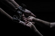 a woman in shackles holds a child by the hand on a black background