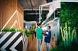 © Atolas/Stocksy - Two colleague creatives talking projects at the office corridor.