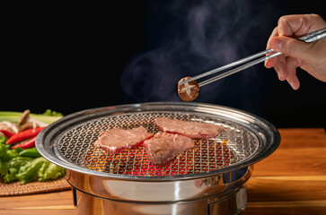 Canvas Print - Hand using chopsticks to pick up Mashroom on hot charcoal Asian BBQ food style, Grilled Beef Sirloin meat on the charcoal stove,Korean BBQ style.