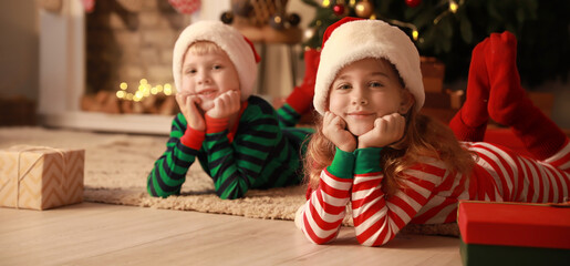 Poster - Cute little children in Santa Claus hats and pajamas at home on Christmas eve