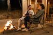 © STUDIO TAURUS/Stocksy - Two young people sitting next to the fire at night