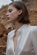 © STUDIO HAMZA/Stocksy - Woman with silk white blouse posing in nature