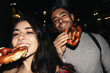 © Pedro Merino/Stocksy - Happy couple eating pretzel at night