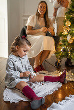 Little Girl Sitting By The Christmas Tree