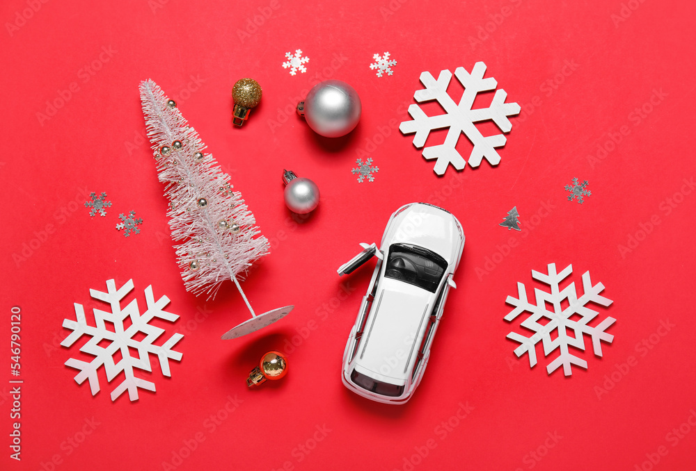 Toy car with Christmas tree, balls and snowflakes on red background