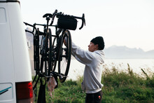 Man Attach Two Bikes To Bike Rack On Back Of Camper Van. Cycling Adventure Travel. Travelling With Bicycle. 