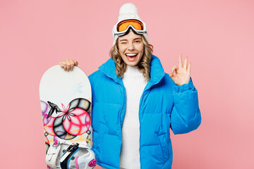 Snowboarder smiling happy cheerful woman wear blue suit goggles mask hat ski padded jacket show ok okay isolated on plain pastel pink background. Winter extreme sport hobby weekend trip relax concept.