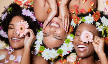 Top View, Beauty And Black Women With Flowers For Skincare In Studio On Brown Background. Makeup Aesthetics, Organic Cosmetics And Group, Friends Or Female Models With Floral Plants For Healthy Skin