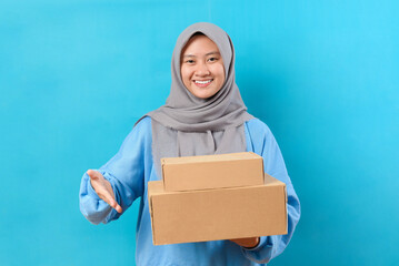 Happy Indonesian woman smiling and holding package parcel box isolated on blue background