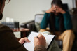 © AnnaStills - Close-up of psychologist making notes in document while talking to patient during session