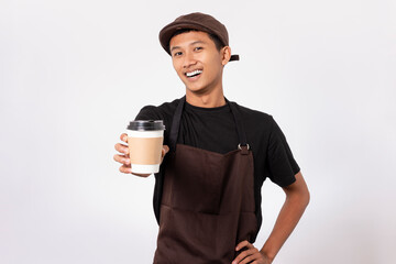 Handsome barista asian man wearing brown apron and black t-shirt isolated over white background. Barista holding coffee cup, serving coffee to customer