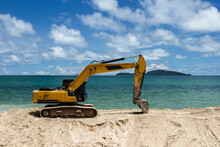 Excavator Is Scooping Up Sand On The Beach With Sky, Sea And Island Background..Excavator Is Digging Sand On The Beach.