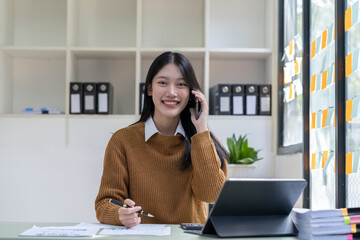 Wall Mural - Portrait young asian businesswoman beautiful charming smiling and talking on the mobile phone in the office.