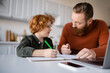 © LIGHTFIELD STUDIOS - bearded man talking to redhead son doing homework near blurred laptop