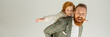 © LIGHTFIELD STUDIOS - Positive dad in jacket looking at camera while playing with redhead son isolated on grey, banner