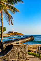 Wall Mural - Old cannon from the time of the empire used in the defense of the city of Salvador in Bahia, with Farol da Barra and the sea in the background