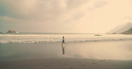 Wall Mural - Pretty woman walks at seaside. Slim female walking along sea water waves on beach at sunset. Travel, vacation, summer concept. Slow motion 4K	