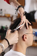 © Andriy Medvediuk - Hands of barber using scissors to cut customer's hair in salon. barber cuts hair, hairstyle. Male customer sitting in chair in hairdressing salon or barbershop. Creating new hair look.