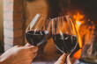 Casal brindando com vinho tinto em lareira no inverno