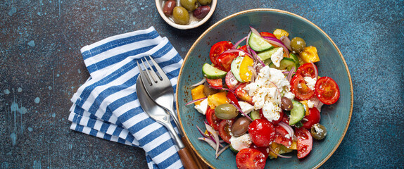 greek fresh healthy colorful salad with feta cheese, vegetables, olives in blue ceramic bowl on rust