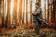 © Khaligo - Portrait of hunter or ranger with gun or rifle in the forest looking out or hunting of some venison, hunting period, autumn season, hunting and people concept