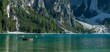 Scenic view of Pragser Wildsee with floating boats on evergreen trees background in the Dolomites